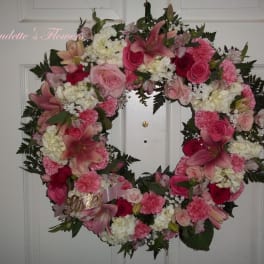 Heart-shaped floral wreath with pink and white flowers on a door