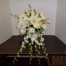 White floral arrangement with lilies and roses on a table