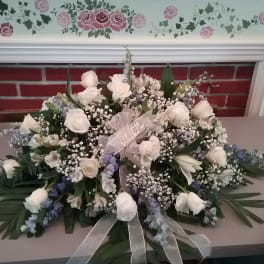 White rose and blue floral arrangement with a sheer ribbon