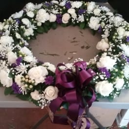 White and purple floral wreath with a large purple ribbon bow
