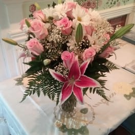Pink roses and lilies arranged in a clear glass vase