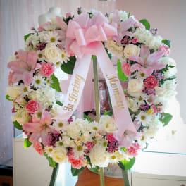 Pink and white floral wreath with a large bow on an easel