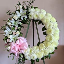 Heart-shaped floral wreath with white flowers and a pink ribbon bow