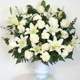 White lilies and roses arranged in a white vase