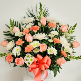 Pink roses and white-orange mixed flowers in a white basket with a coral bow