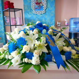 Large white and blue floral arrangement with ribbon on a table
