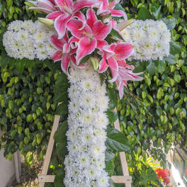 Pink lilies and white chrysanthemums arranged in a cross on a stand