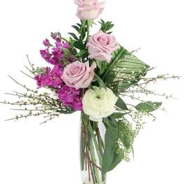 Pink and white roses with purple flowers in a clear glass vase