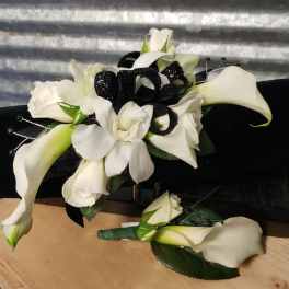 White calla lilies and orchids with black ribbon on a black cushion