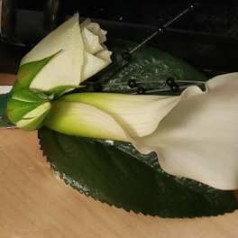 White calla lily boutonniere with a dark green leaf
