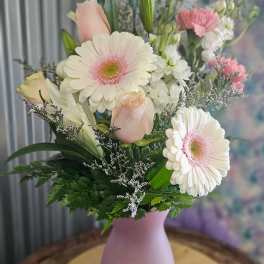 Pastel bouquet of gerbera daisies, roses, lilies, and carnations in a pink vase