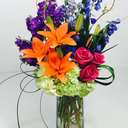 Colorful bouquet of lilies, roses, and hydrangeas in a glass vase