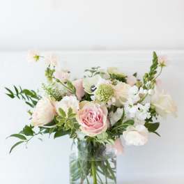Pastel bouquet of pink and white flowers in a clear glass vase