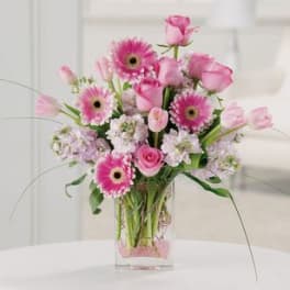 Pink gerberas and roses arranged in a clear glass vase