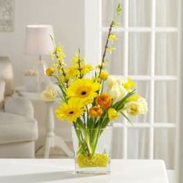 Yellow and white flowers arranged in a clear glass vase