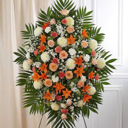 Standing floral spray with orange lilies, peach roses, and white blooms