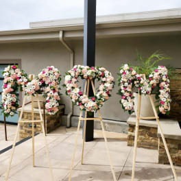 Four floral wreaths on wooden easels outdoors
