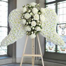 White floral angel wings on a wooden stand with roses in the center