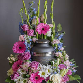 Funeral urn surrounded by pink, white, and blue flowers
