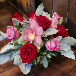 Bouquet of red and pink roses with a pink orchid in a glass vase