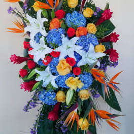 Tall standing floral spray with lilies, roses, hydrangeas, and bird-of-paradise