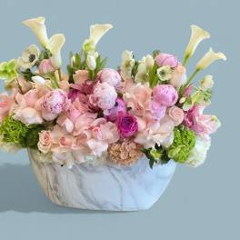 Pastel floral arrangement in a marble-patterned vase with calla lilies and roses