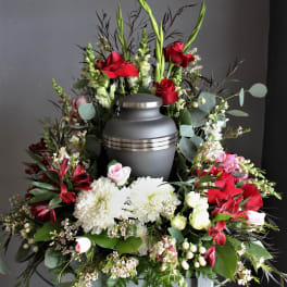 Funeral urn surrounded by red and white flowers in a wreath arrangement