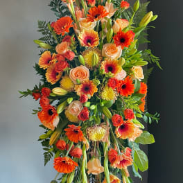 Tall standing floral spray with orange and peach blooms on an easel