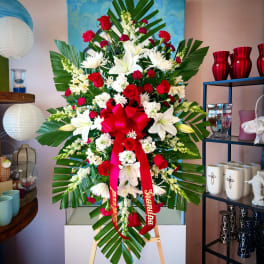 Large standing floral spray with red and white flowers and a red ribbon