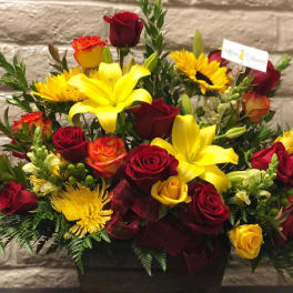 Bouquet of red and yellow roses with lilies and sunflowers in a black vase