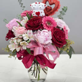 Pink and red bouquet in a glass vase with teddy bears and a heart decoration