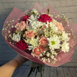 Handheld bouquet of white daisies, pink roses, and carnations wrapped in pink paper
