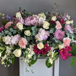 Large pastel floral arrangement with roses, chrysanthemums, and trailing lavender flowers