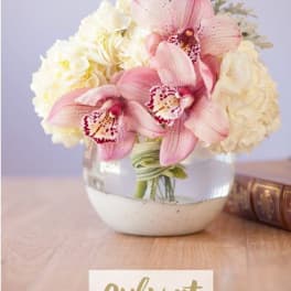 Pink orchids and white hydrangeas arranged in a clear glass vase