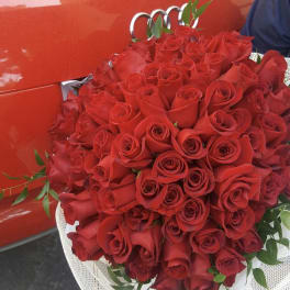Large bouquet of red roses with greenery, wrapped in white mesh