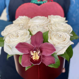 White roses in a red heart-shaped box with a pink orchid