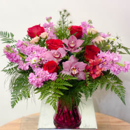 Pink and red mixed bouquet in a magenta glass vase