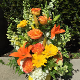 Orange roses and lilies with yellow daisies in a yellow vase