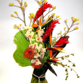 Tropical flower arrangement in a glass vase with red and orange blooms