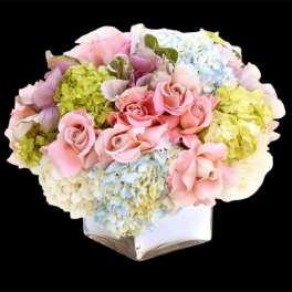 Pink roses and pastel hydrangeas arranged in a white vase