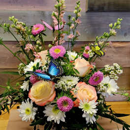 Mixed bouquet with peach roses, white daisies, and pink blooms with butterfly picks