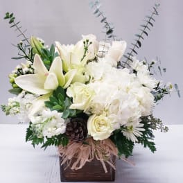 White floral arrangement with lilies, roses, and hydrangeas in a wooden box