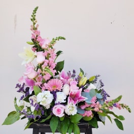 Pink and white floral arrangement with lilies and roses in a low container