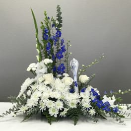 White and blue floral arrangement with tall spikes in a low container