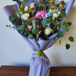 Mixed bouquet of pastel flowers wrapped in lavender paper