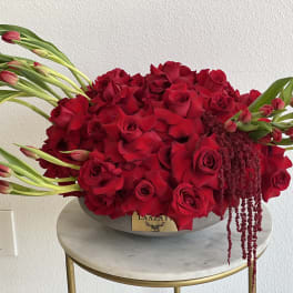 Large red rose arrangement with tulips in a low oval container