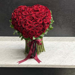 Heart-shaped bouquet of red roses with a ribbon tie