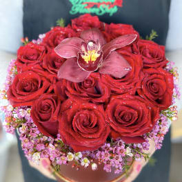 Red rose bouquet with a central orchid in a round box