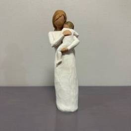 Small figurine of a woman holding a child, in white clothing