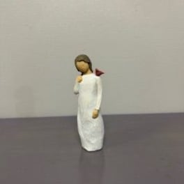 Small angel figurine in a white robe holding a red flower